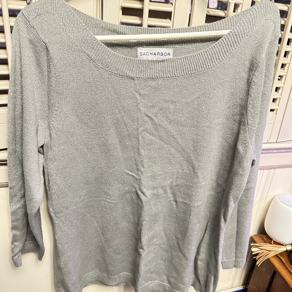 Women’s gray/silverer light sweater with button accents on shoulders.
